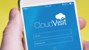 a hand holds a smartphone open to the CloudVisit login page